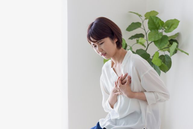 痛みを感じて胸を押さえている女性